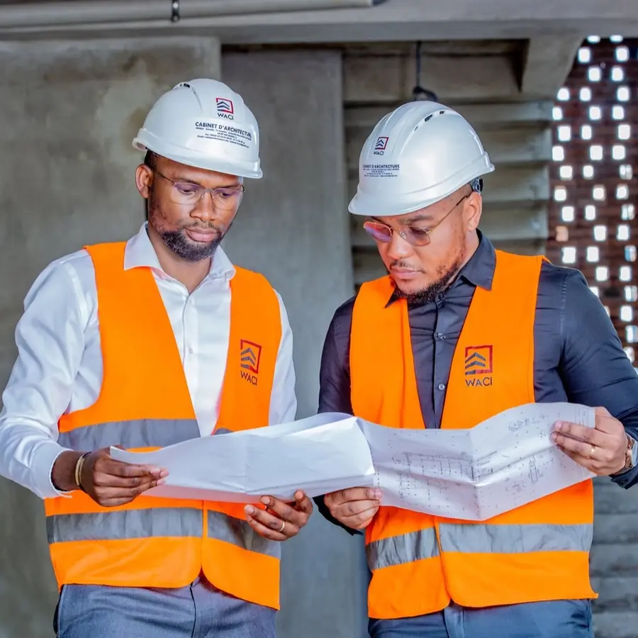 Deux ingénieurs consultent des plans sur un chantier de WACI
